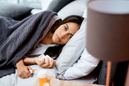 Beat the flu by staying in bed. a young woman recovering from an illness in bed at home.