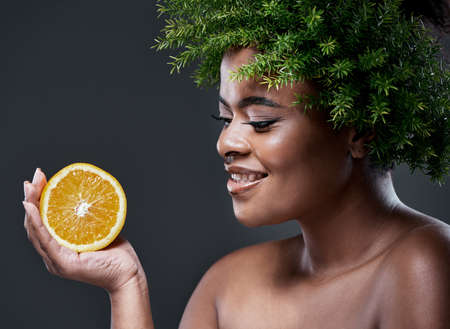 High in vitamin C and antioxidants. a beautiful woman holding an orange and wearing a leaf wreath on...