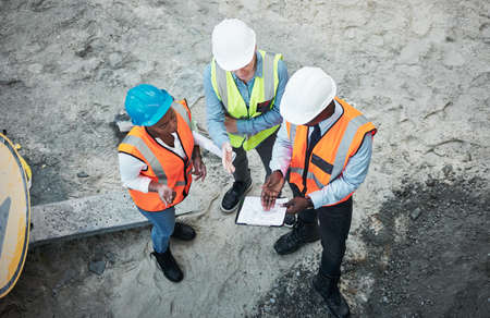 The hardest work happens out in the field. a group of builders going over building plans at a construction site.の写真素材