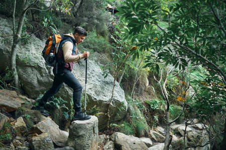 Go wild for a while. a young man using a walking pole while hiking through the mountains.