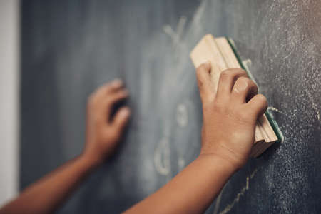 Lets try this again. an unrecognizable boy using the duster to clean a blackboard.の写真素材