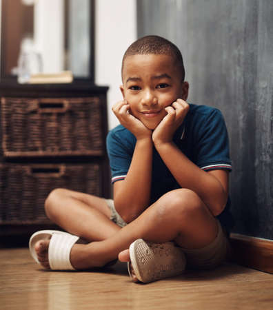 I trying to think of something fun to do. an adorable little boy sitting at home.の写真素材