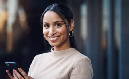 Communication is key. Cropped portrait of an attractive young businesswoman sending a text while...