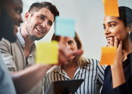 Theyre a team that succeeds. a group of business colleagues brainstorming on a glass wipe board in their office.の写真素材