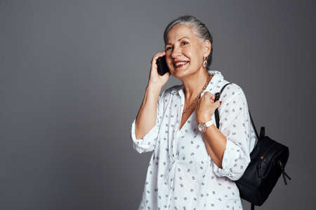 Lets stay in touch. a senior woman carrying her handbag while talking on her cellphone.の写真素材