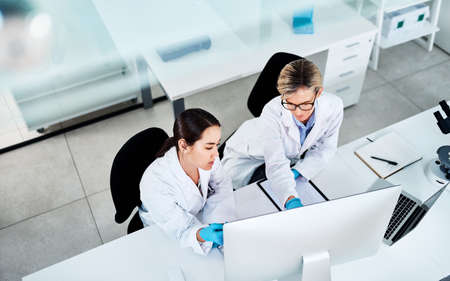 Putting their heads together on a new mystery. two scientists working together on a computer in a lab.の写真素材
