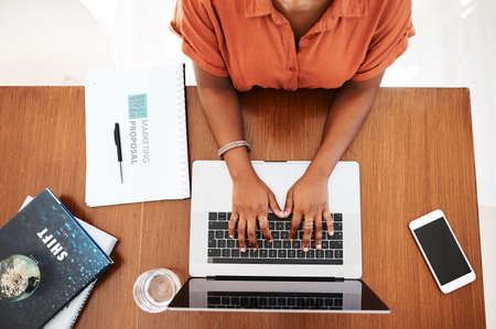 Lets get to work then. High angle shot of an unrecognisable businesswoman working on a laptop in an...