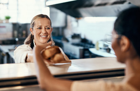 As fresh as her customers deserve. a woman buying freshly made baguettes at a bakery.の写真素材