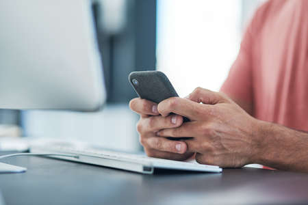 Smart tech is a must for a search engine specialist. a businessman using a smartphone at his desk in a modern office.の写真素材