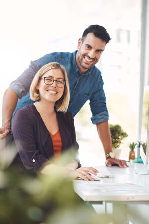 Teamwork between colleagues, coworkers and business partners working together in an office to achieve success. Portrait of two employees looking happy, confident and ready in their design companyの写真素材