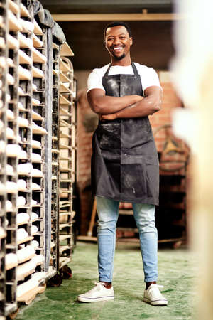 Come and check out the best bakery in town. a confident young man working in a bakery.の写真素材