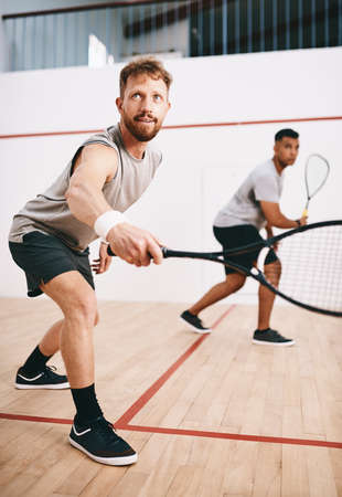 He only has eyes for the ball. two young men playing a game of squash.の写真素材