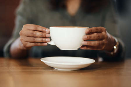 You cant keep me away from their coffee. a woman having coffee in a cafe.の写真素材