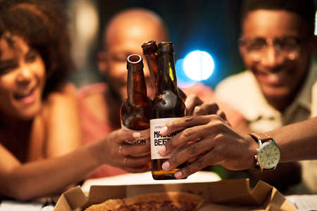 Lets drink to our success. a group of businesspeople having beers at the office while working late.
