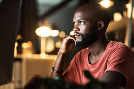 Its taking me all day to crack this. a business man using his computer while working late at the office.の写真素材