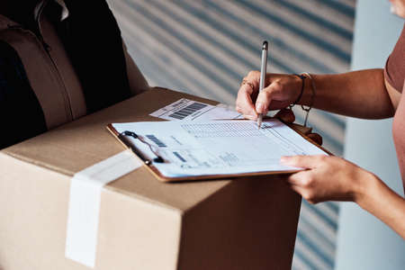 Your parcel will be released once you sign for it. Closeup shot of an unrecognisable woman signing...
