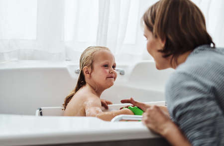 Is the water alright. an adorable little girl bonding with her mother while taking a bath at home.の写真素材