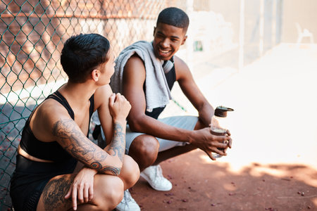 Just happy to be hanging. two sporty young people chatting to each other against a fence outdoors.の写真素材