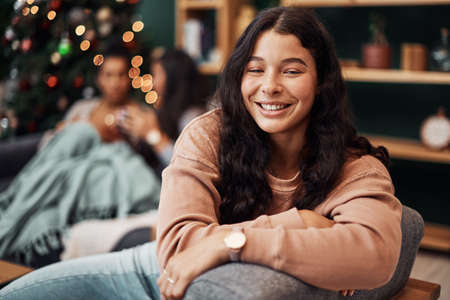 All I want for Christmas, Ive already got. a beautiful young woman relaxing on the sofa with her friends in the background during Christmas at home.の写真素材