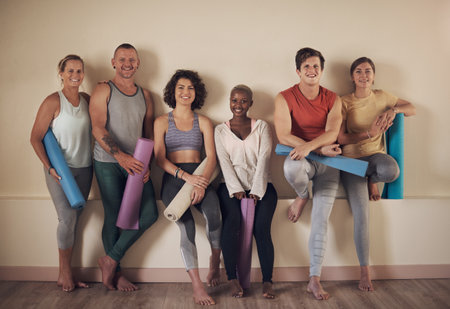 This is the best yoga group. Full length portrait of a diverse group of yogis sitting together and bonding after an indoor yoga session.の写真素材