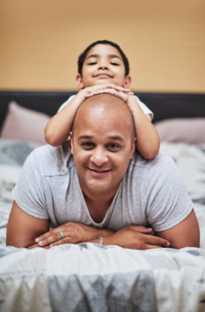 Theres something on my head. Portrait of a cheerful little boy hanging on his fathers back while...