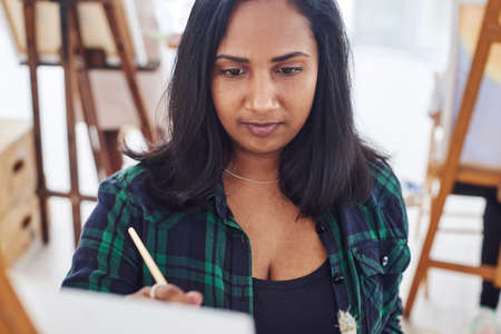 Forget everything else and start creating. a beautiful young woman painting in a art studio.