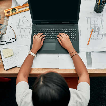 She has a busy day ahead of her. High angle shot of an architect working on a laptop in an office.の写真素材
