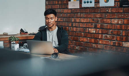 People are rating his services high online. a handsome young male fitness instructor using a laptop while working in a gym.の写真素材