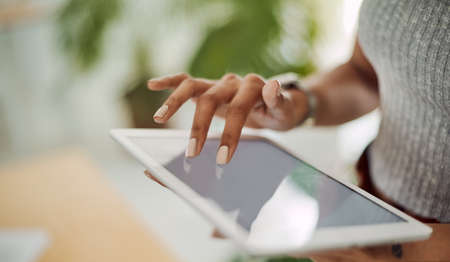 Getting in touch with the the business world on a global scale. Closeup shot of an unrecognisable businesswoman using a digital tablet in an office.の写真素材