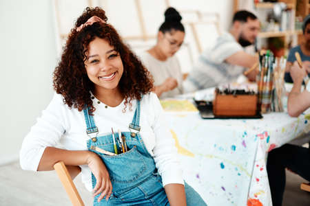 Cropped portrait of an attractive young woman sitting with her friends during an art class in the studio.の写真素材