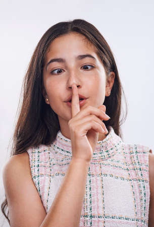 Be yourself. an attractive teenage girl standing with her finger on her lips against a white studio background.の写真素材