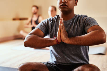 Immersed in the magic of yoga. a group of young men and women meditating in a yoga class.の写真素材