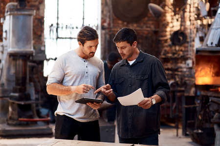 We run our workshop smart and efficiently. two handsome young using a digital tablet while working...