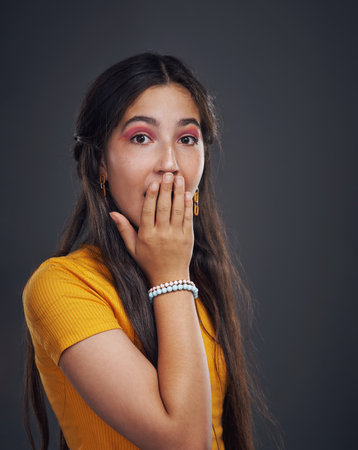 No way. Cropped portrait of an attractive teenage girl standing alone and looking surprised against a dark background in the studio.の写真素材