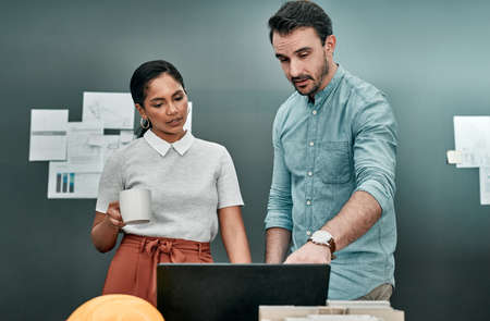 I digitised these as well. two architects working together on a laptop in an office.
