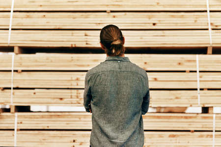 Ive got plenty of options to choose from. Rearview shot of young carpenter looking at a piles of...