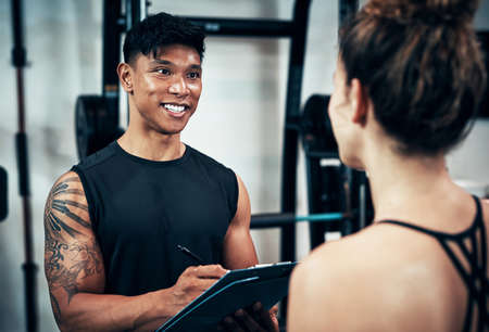 Lets just do a quick body assessment. a sporty young woman talking to a fitness trainer at the gym.