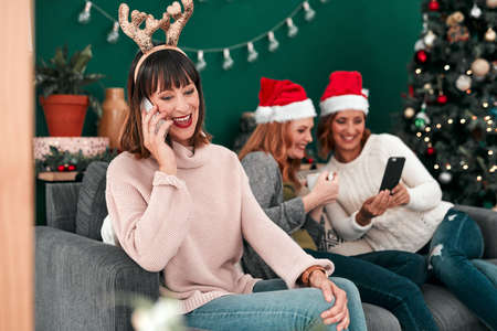 We wish you could join us. three attractive woman using their cellphones on the sofa at home.の写真素材