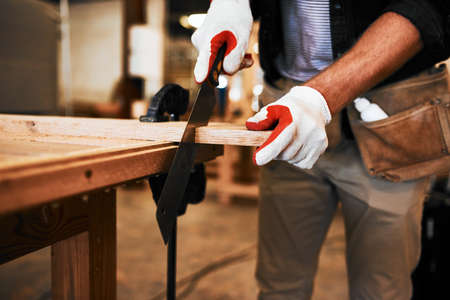 Make sure youre always cutting straight and on line. an unrecognizable carpenter cutting wood inside...