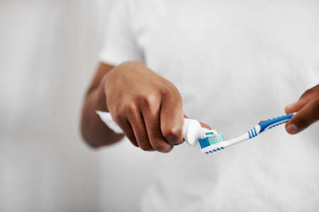 The right toothpaste matters. an unrecognizable man putting toothpaste on his toothbrush.の写真素材