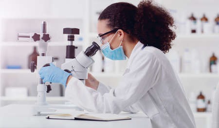 Conducting another careful test. a young scientist using a microscope in a lab.の写真素材