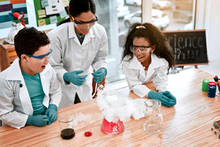 Nothing says fun like a science experiment. an adorable little boy and girl conducting a scientific experiment with their teacher at school.の写真素材