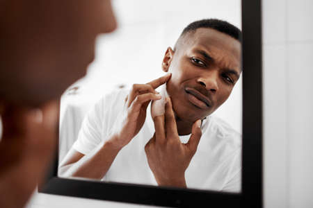 I dont want people to stare at it. a young man squeezing pimples in the bathroom mirror.
