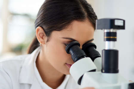 Things are a lot different under the lens. a young scientist using a microscope in a lab.