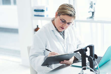 Getting ready to file her report on the experiment. an attractive young female scientist filling a...