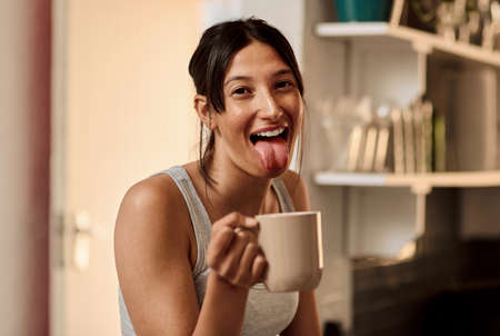 When the caffeine kicks in. a young woman enjoying a playful moment while having a cup of coffee at...
