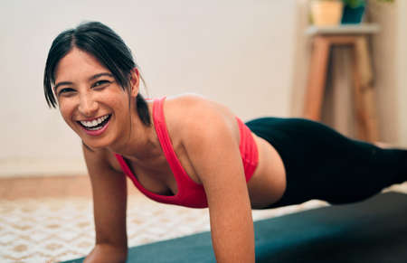Activate those endorphins and start feeling good. Portrait of a happy young woman exercising at home.の写真素材
