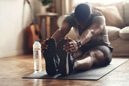 Keep pushing yourself to become the best. a sporty young man stretching his legs while exercising at...