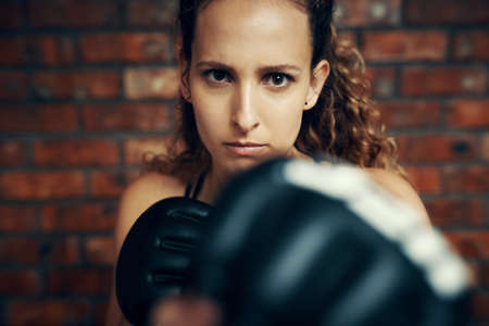 Shes as bad as they get. Cropped portrait of a female kick boxer practicing at the gym.の写真素材