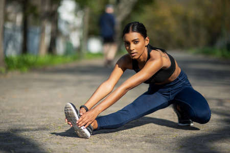 Getting ready to run her heart out. Portrait of a sporty young woman stretching her legs while...